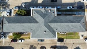 Aerial view of a newly installed asphalt shingle roof on a commercial property completed by Visionaire Construction