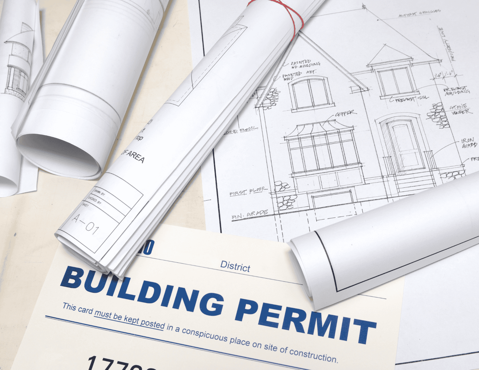 http://Rolled%20construction%20blueprints%20and%20a%20building%20permit%20form%20on%20a%20desk