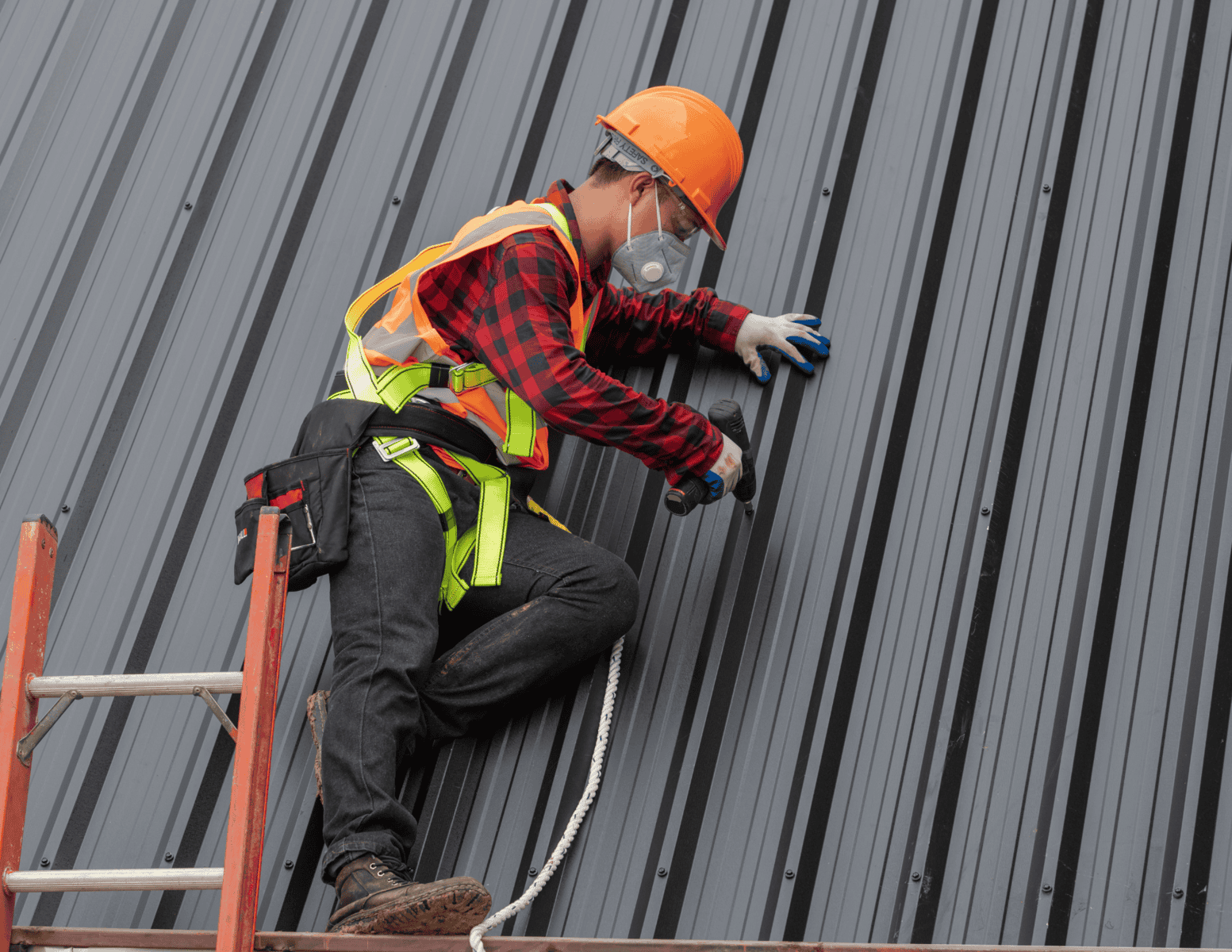 http://Worker%20in%20safety%20gear%20installing%20metal%20roofing%20panels%20on%20a%20steep%20roof